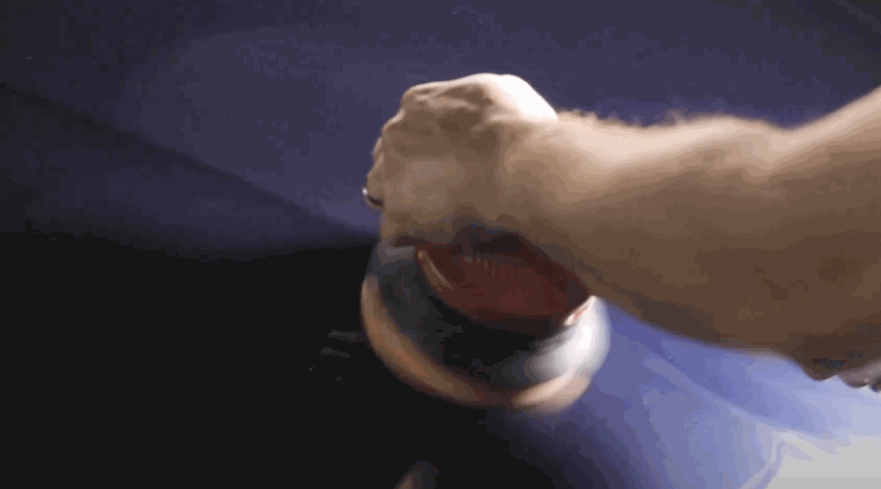 A person uses a dual-action polisher on a car’s painted surface, prepping it for paint protection film with smooth, circular buffing.