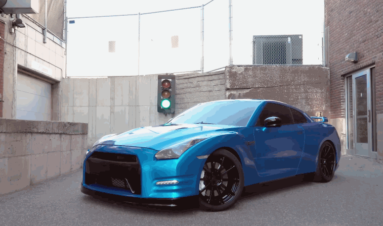 Blue sports car parked in an alley with dark tinted windows and glossy finish showcasing a professional vinyl wrap that enhances color depth and protects the original paint.