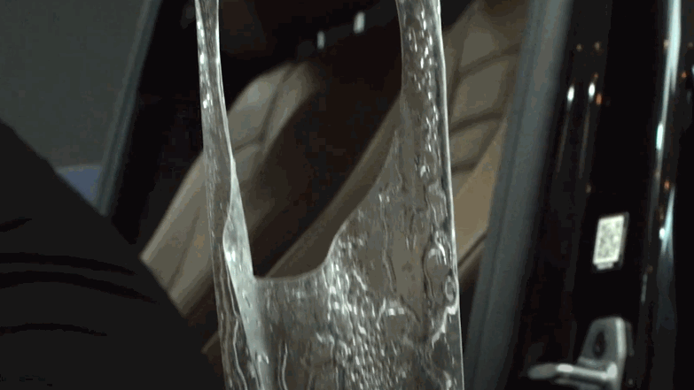 Clear paint protection film being applied to a car door handle area with water bubbles visible as the film is positioned for a precise fit.
