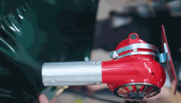 A red heat gun warms commercial fleet graphics on a dark vehicle panel during installation. The close up shows the film conforming to the surface for a smooth finish.