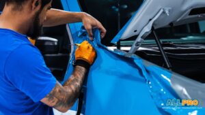Installer trims blue vinyl wrap around the rear tailgate area of a Jeep.